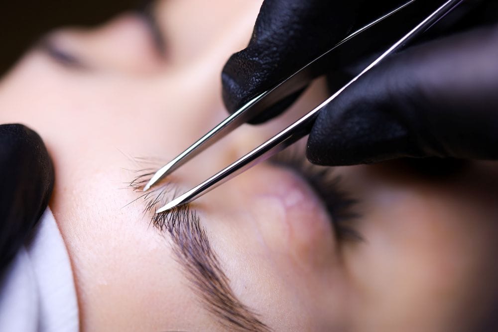 Technician applying eyebrow extensions with micro tools